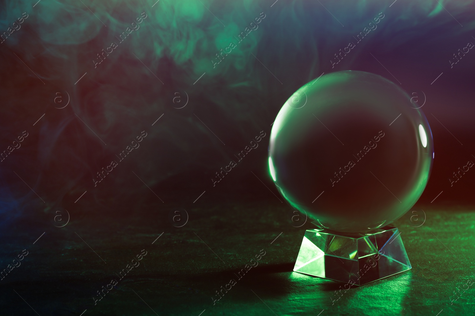 Photo of Crystal ball on table and smoke against dark background, space for text. Predictions of future