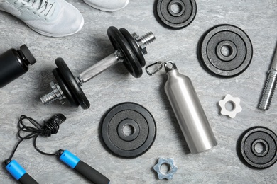 Photo of Flat lay composition with dumbbell and fitness accessories on grey background