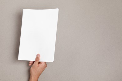 Man holding sheets of paper on grey background, closeup. Mockup for design