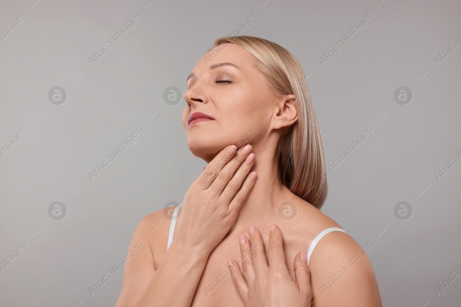 Photo of Beautiful woman touching her neck on grey background