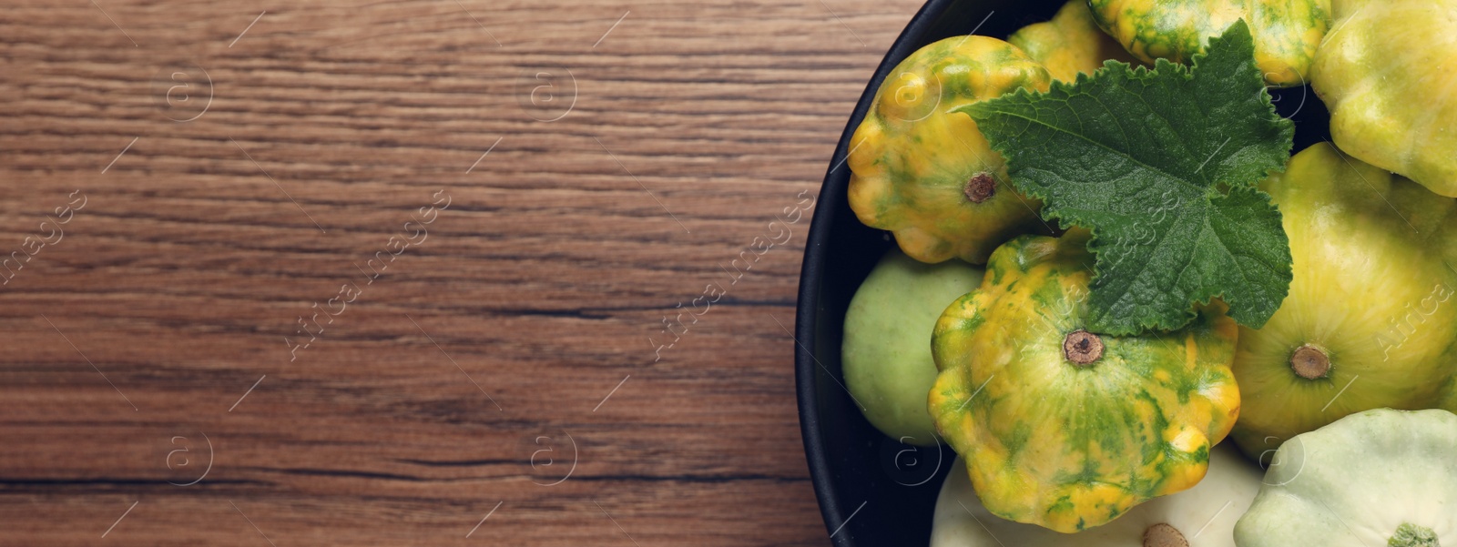 Image of Fresh pattypan squashes in bowl on wooden table, top view with space for text. Banner design