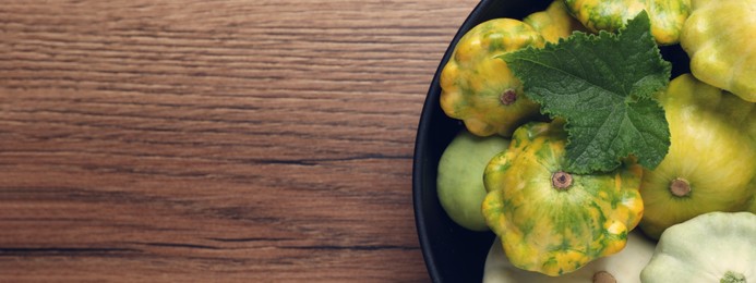 Fresh pattypan squashes in bowl on wooden table, top view with space for text. Banner design