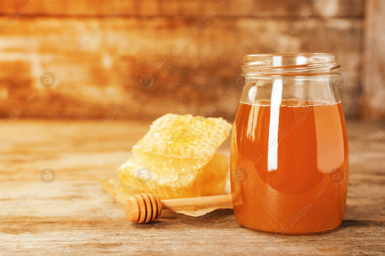 Image of Jar of tasty fresh honey and dipper on wooden table