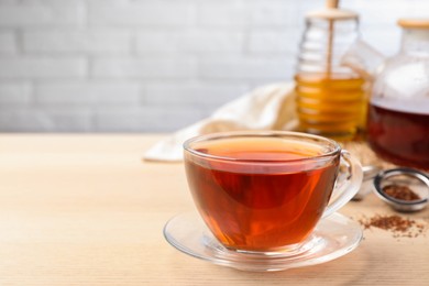 Photo of Freshly brewed rooibos tea on wooden table. Space for text