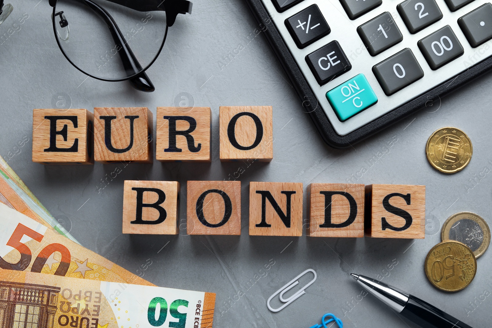 Photo of Flat lay composition with banknotes and word Eurobonds made of wooden cubes on grey table