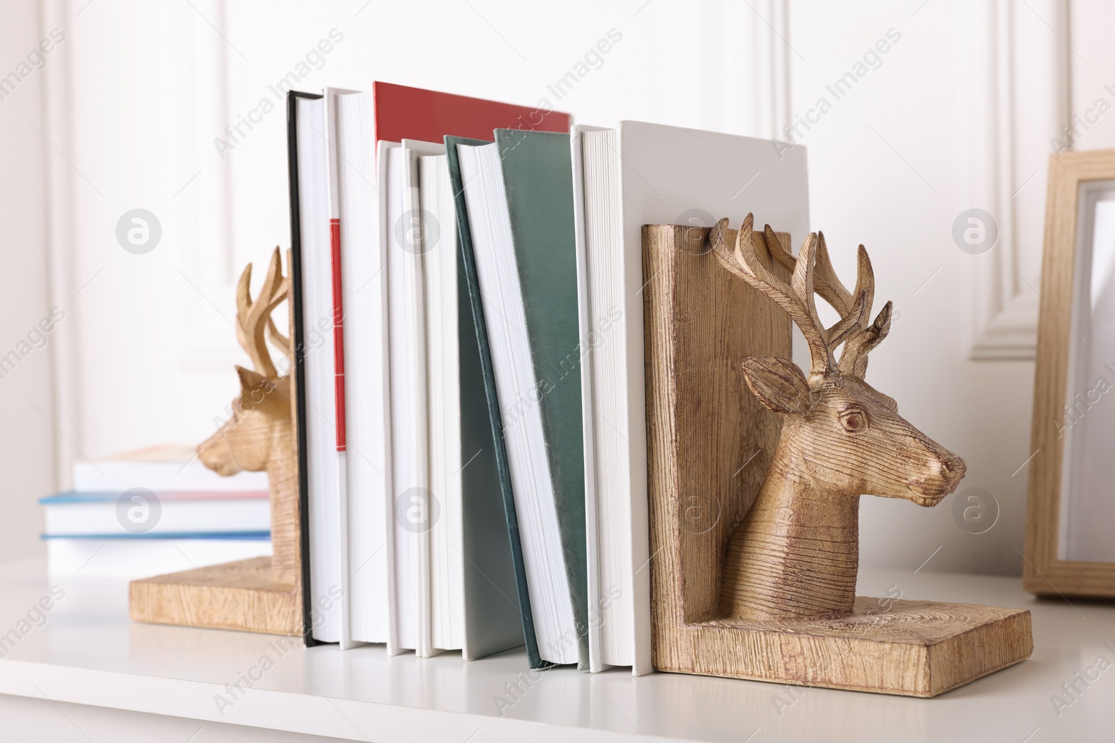 Photo of Wooden deer shaped bookends with books on table indoors