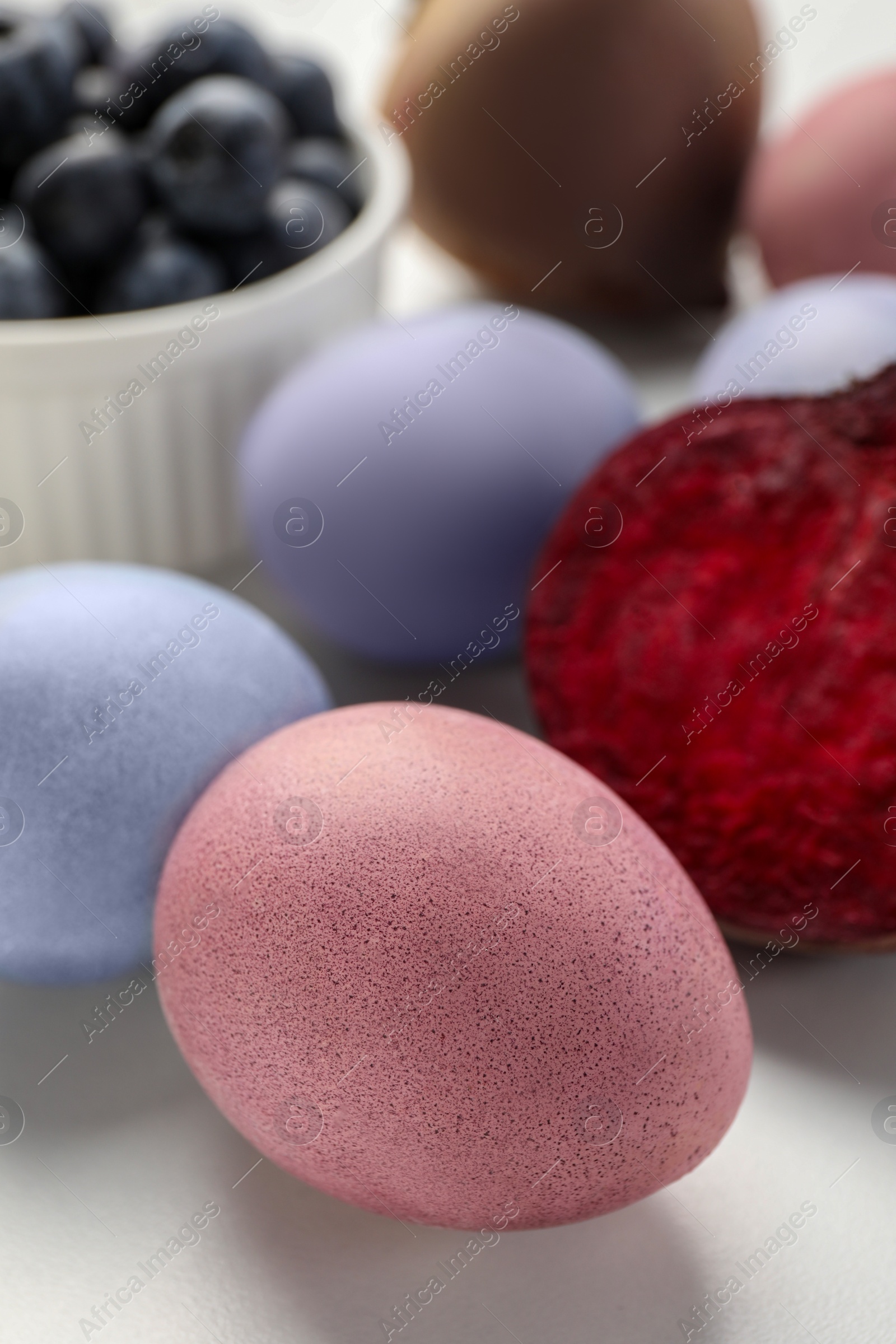 Photo of Colorful Easter eggs painted with natural dyes on white table, closeup