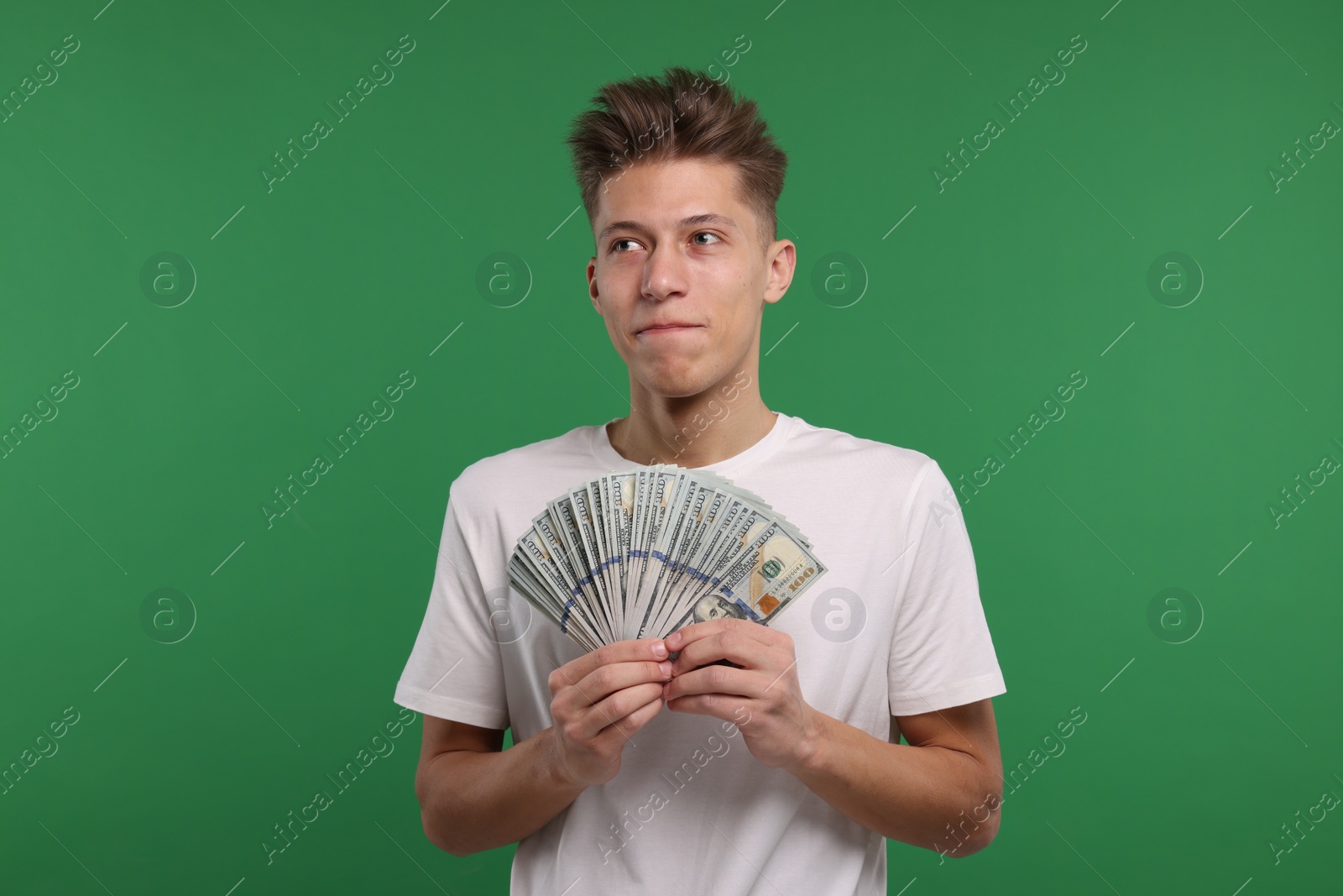 Photo of Handsome man with dollar banknotes on green background