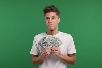 Photo of Handsome man with dollar banknotes on green background