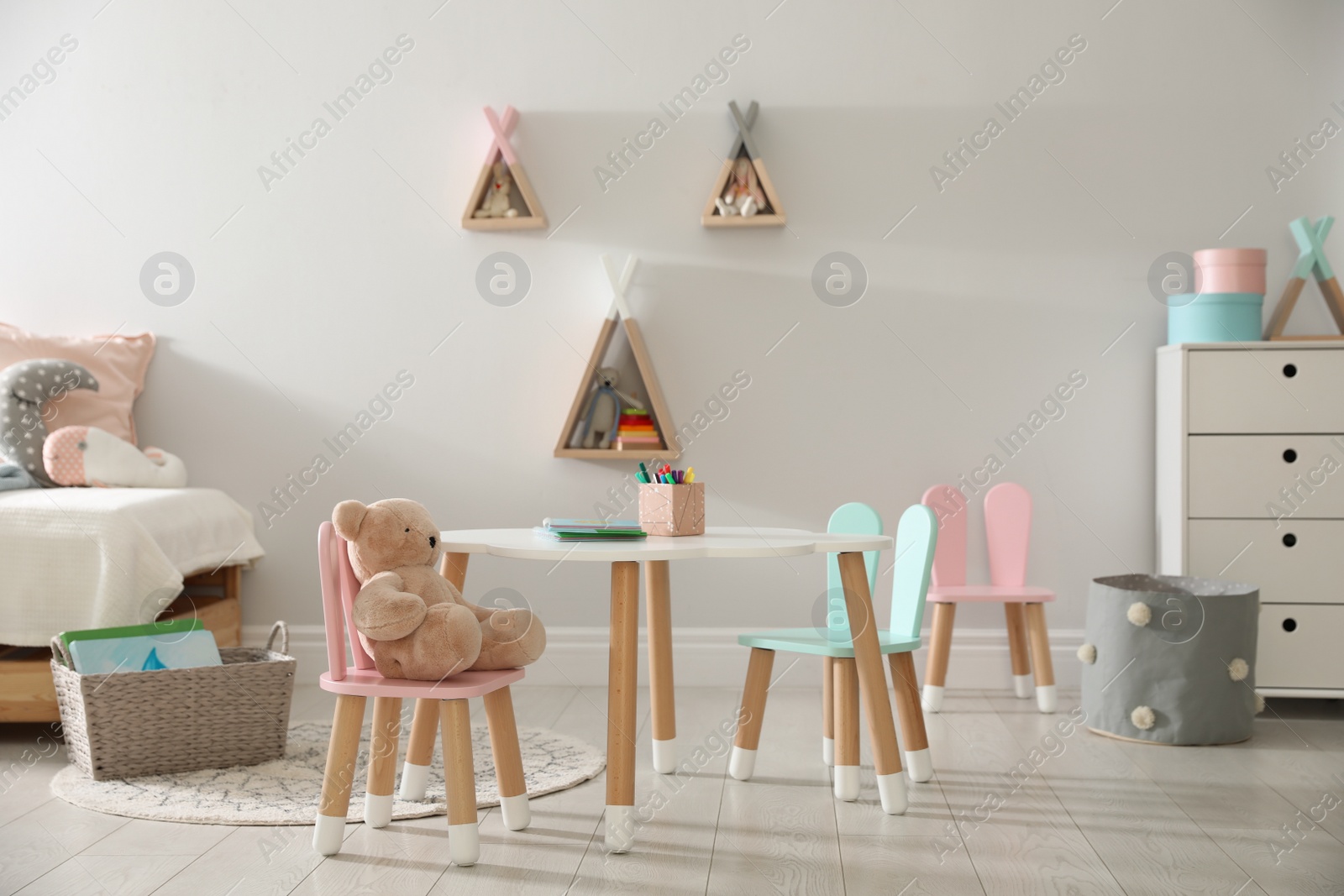 Photo of Small table and chairs with bunny ears in children's room interior