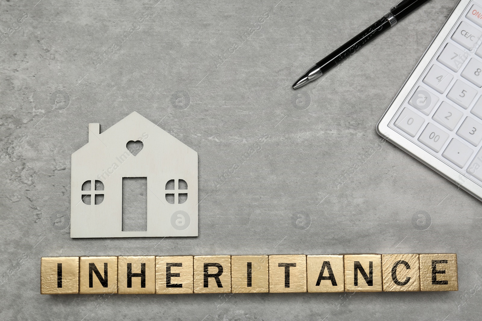 Photo of Word Inheritance made with cubes, house model and pen on light gray table, flat lay