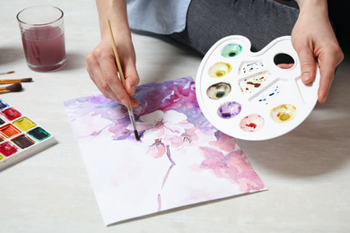 Woman painting flowers with watercolor on floor, closeup