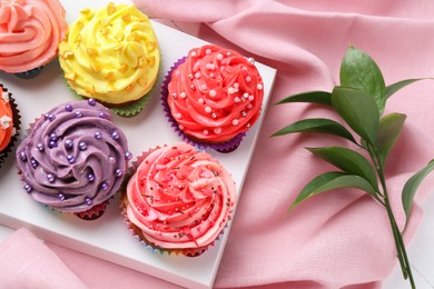 Photo of Delicious cupcake with bright cream on pink fabric, top view
