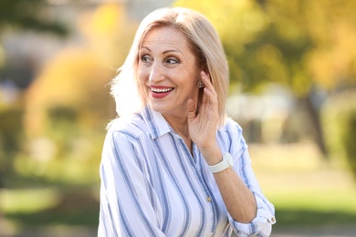 Portrait of happy mature woman in park on sunny day