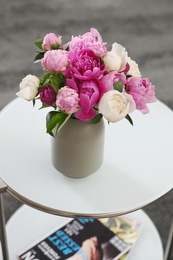 Photo of Vase with bouquet of beautiful peonies on table in room