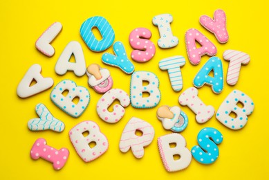 Photo of Set of baby shower cookies on yellow background, flat lay