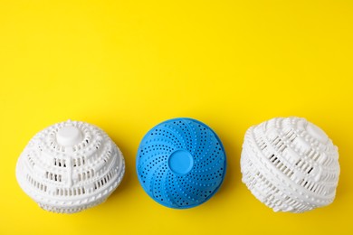 Photo of Laundry dryer balls on yellow background, flat lay. Space for text