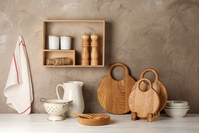 Photo of Wooden cutting boards, dishware, kitchen utensils and towel on white table