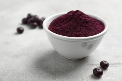 Photo of Bowl with acai powder on gray table