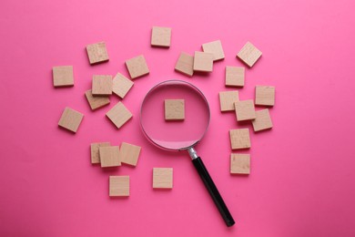 Magnifying glass and pieces of wood on pink background, flat lay
