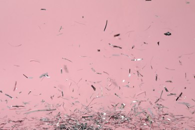 Photo of Shiny silver confetti falling down on pink background