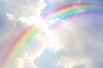 Image of Beautiful view of bright rainbow in blue sky on sunny day