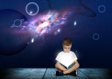 Cute little boy reading magic book. Night sky with stars and planets on background 