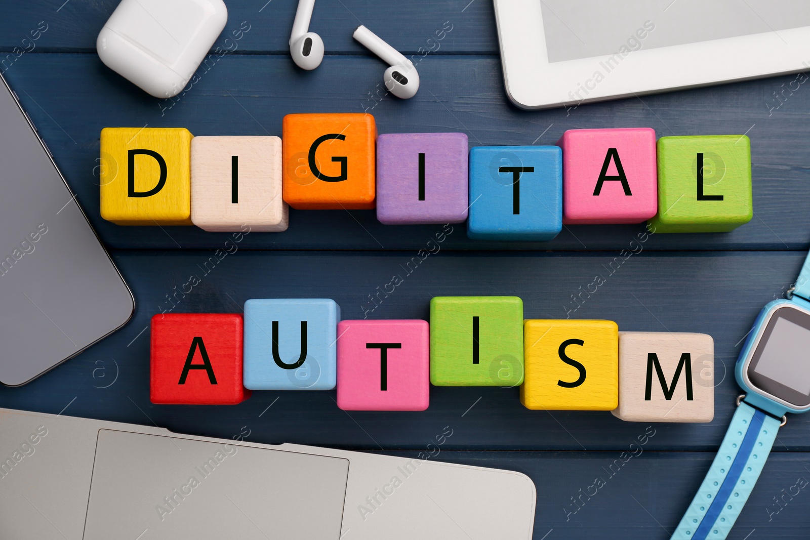 Photo of Phrase Digital Autism made of colorful cubes and devices on blue wooden table, flat lay. Addictive behavior