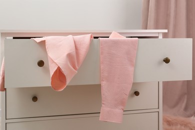 Photo of Pink shirt on white chest of drawers indoors