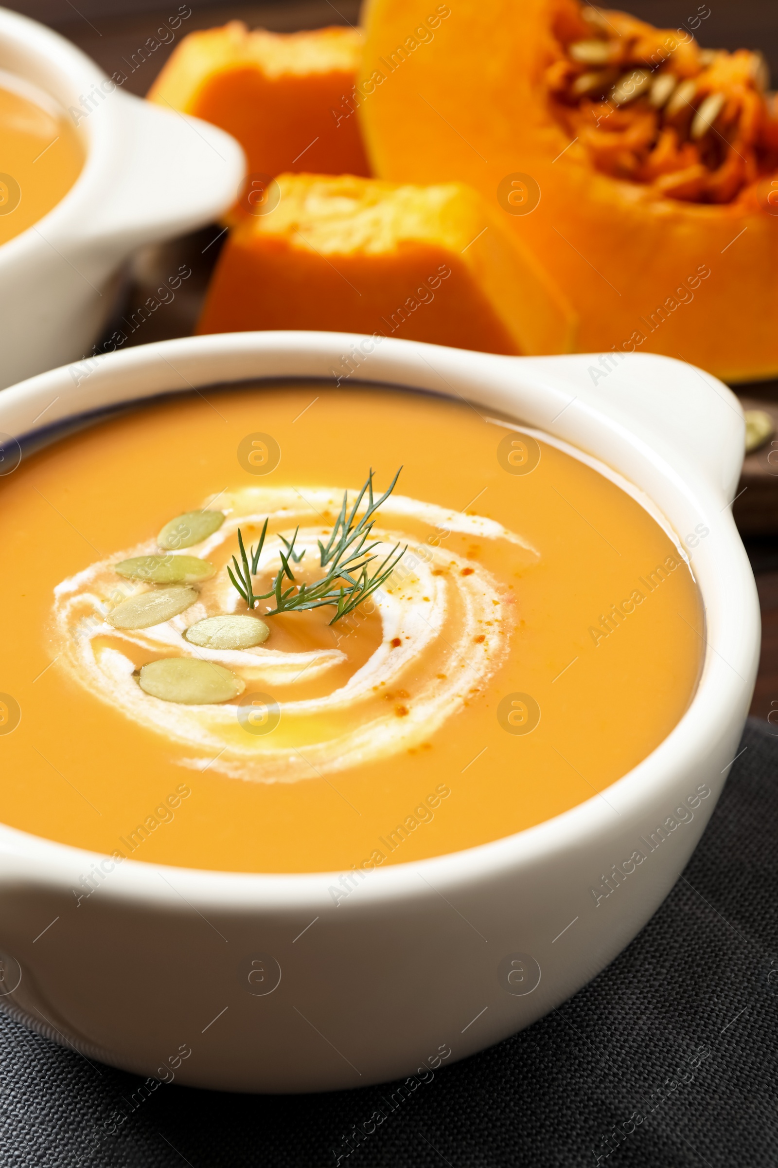 Photo of Tasty creamy pumpkin soup with dill and seeds in bowl on table