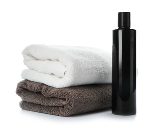 Photo of Folded towels and shampoo isolated on white