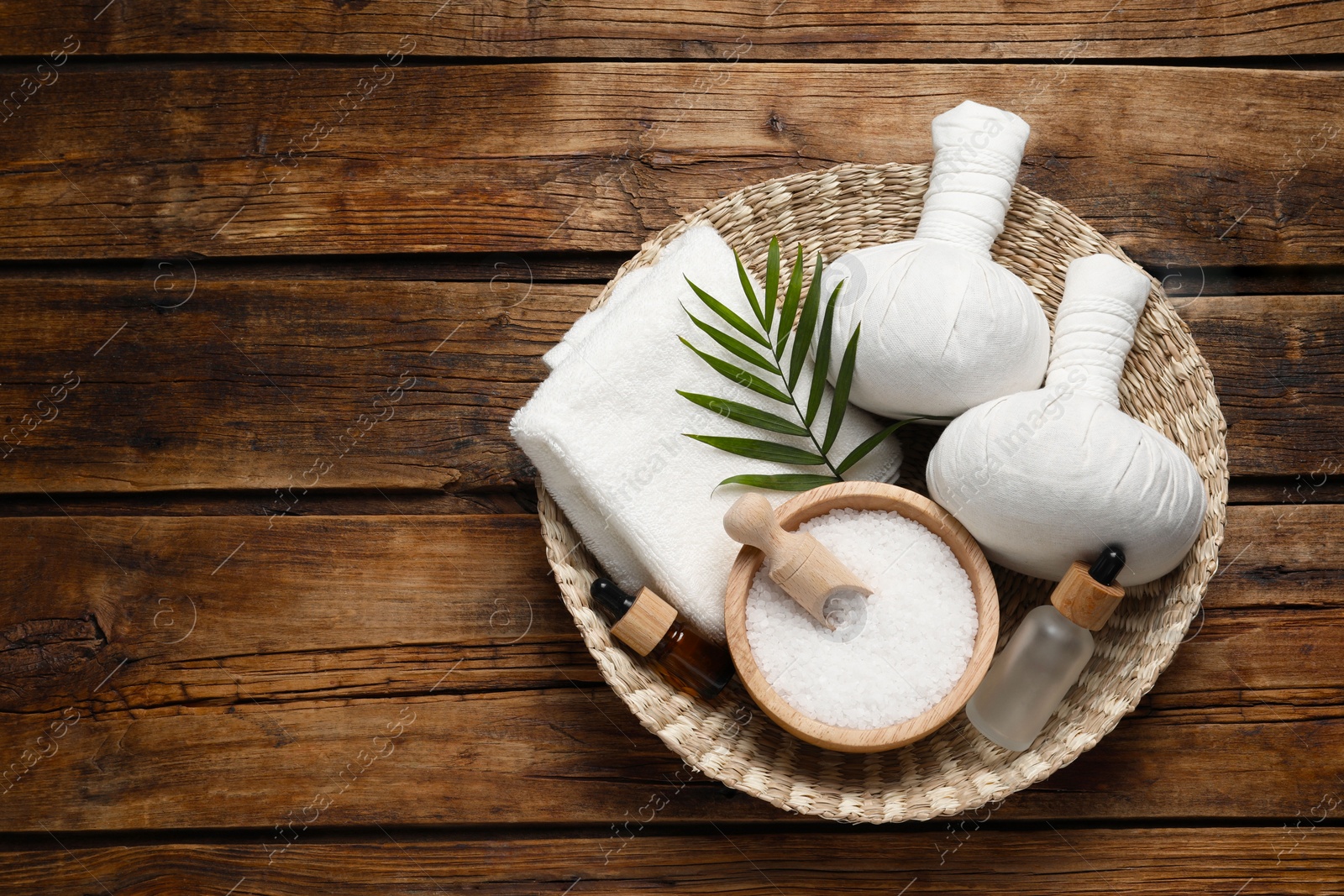 Photo of Composition with herbal massage bags and other spa products on wooden table, top view. Space for text