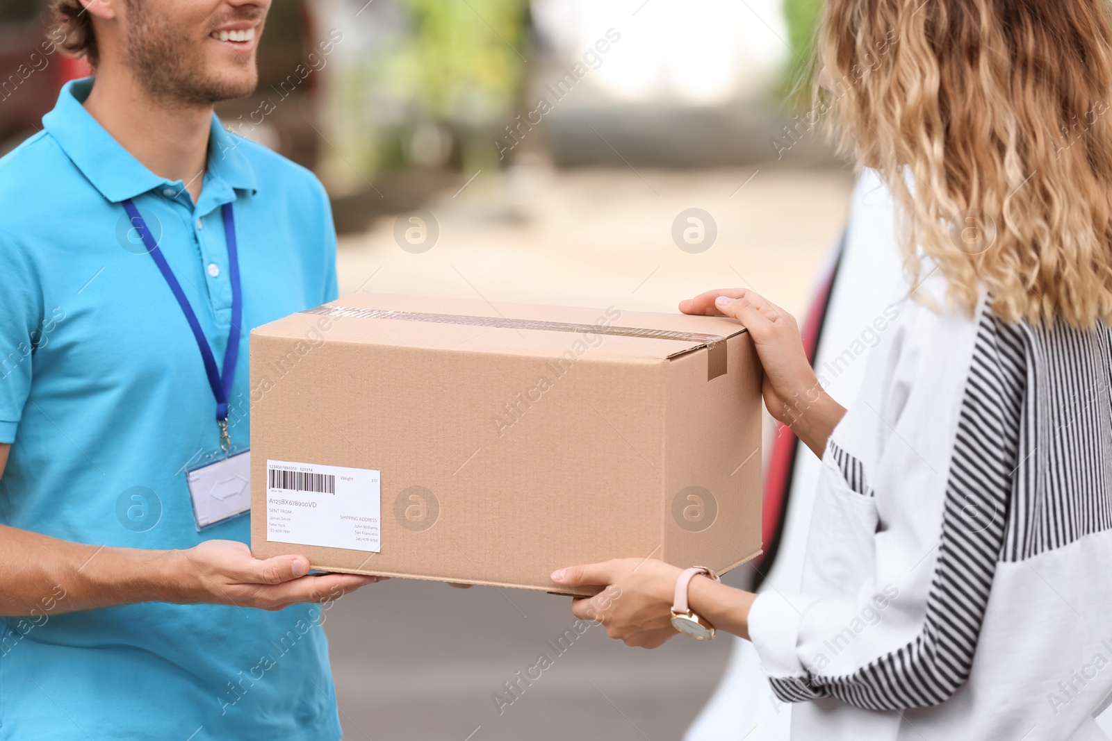 Photo of Young courier delivering parcel to woman outdoors