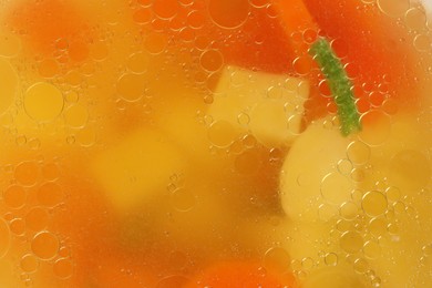 Delicious soup with carrots and potatoes as background, top view