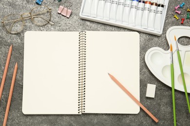 Flat lay composition with blank sketchbook on grey stone table. Space for text