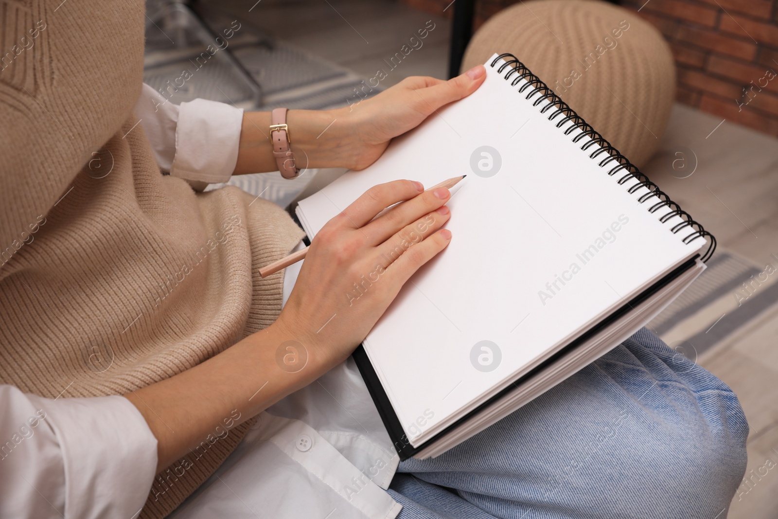 Photo of Woman drawing in sketchbook with pencil at home, closeup