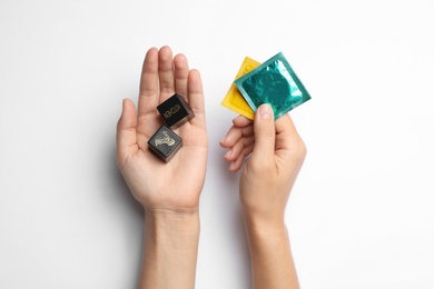 Photo of Woman with dice and condoms on white background, top view. Sex game