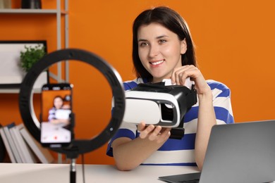 Photo of Smiling technology blogger recording video review about virtual reality headset at home