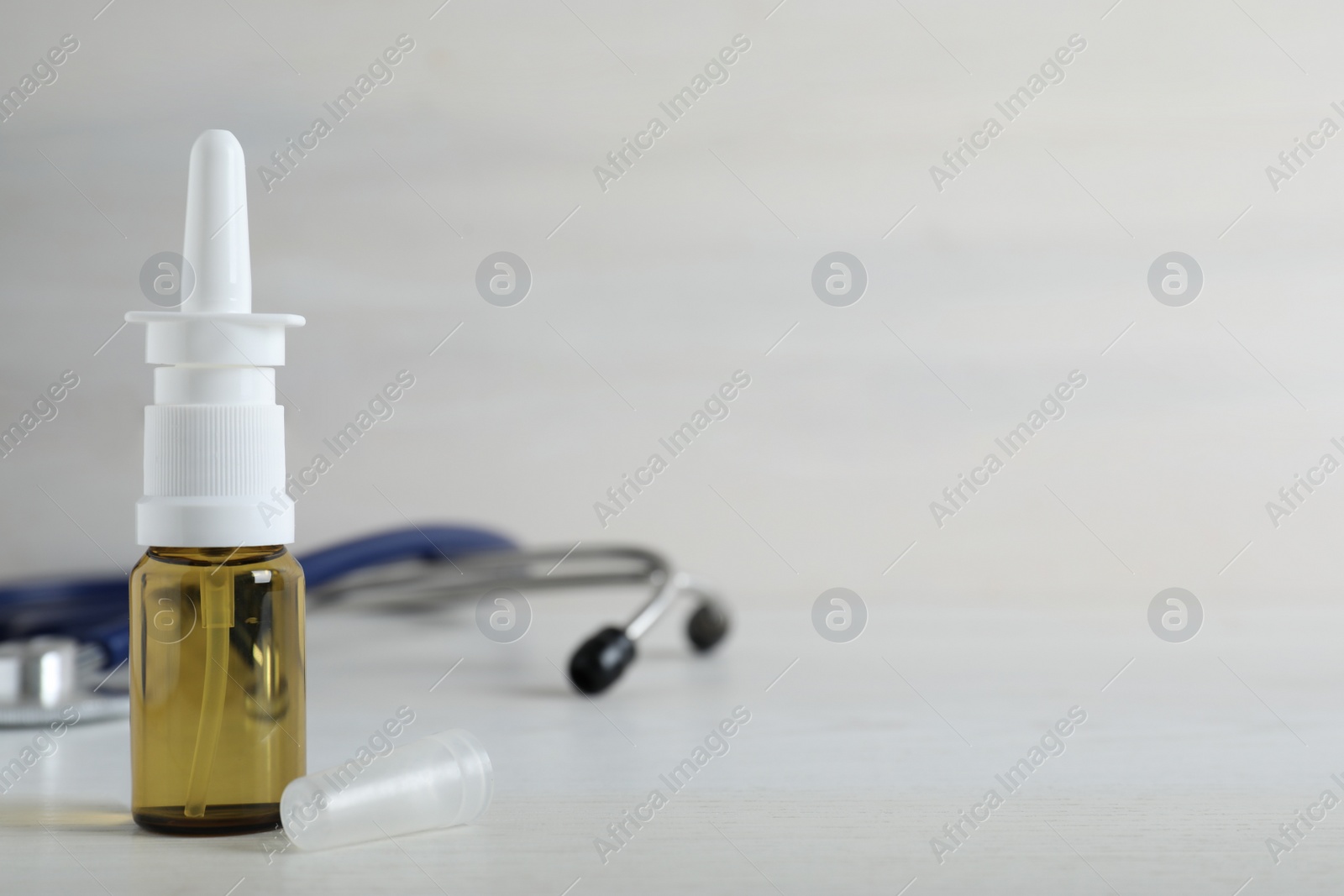 Photo of Bottle of nasal spray on white wooden table. Space for text