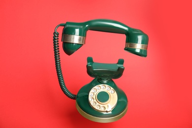 Photo of Green vintage corded phone on red background