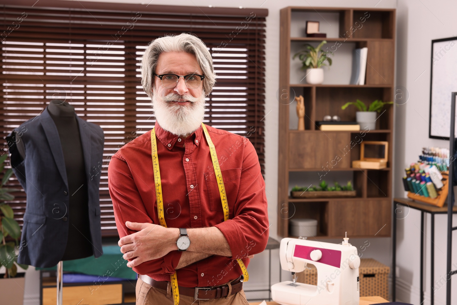 Photo of Professional tailor with measuring tape in workshop, space for text