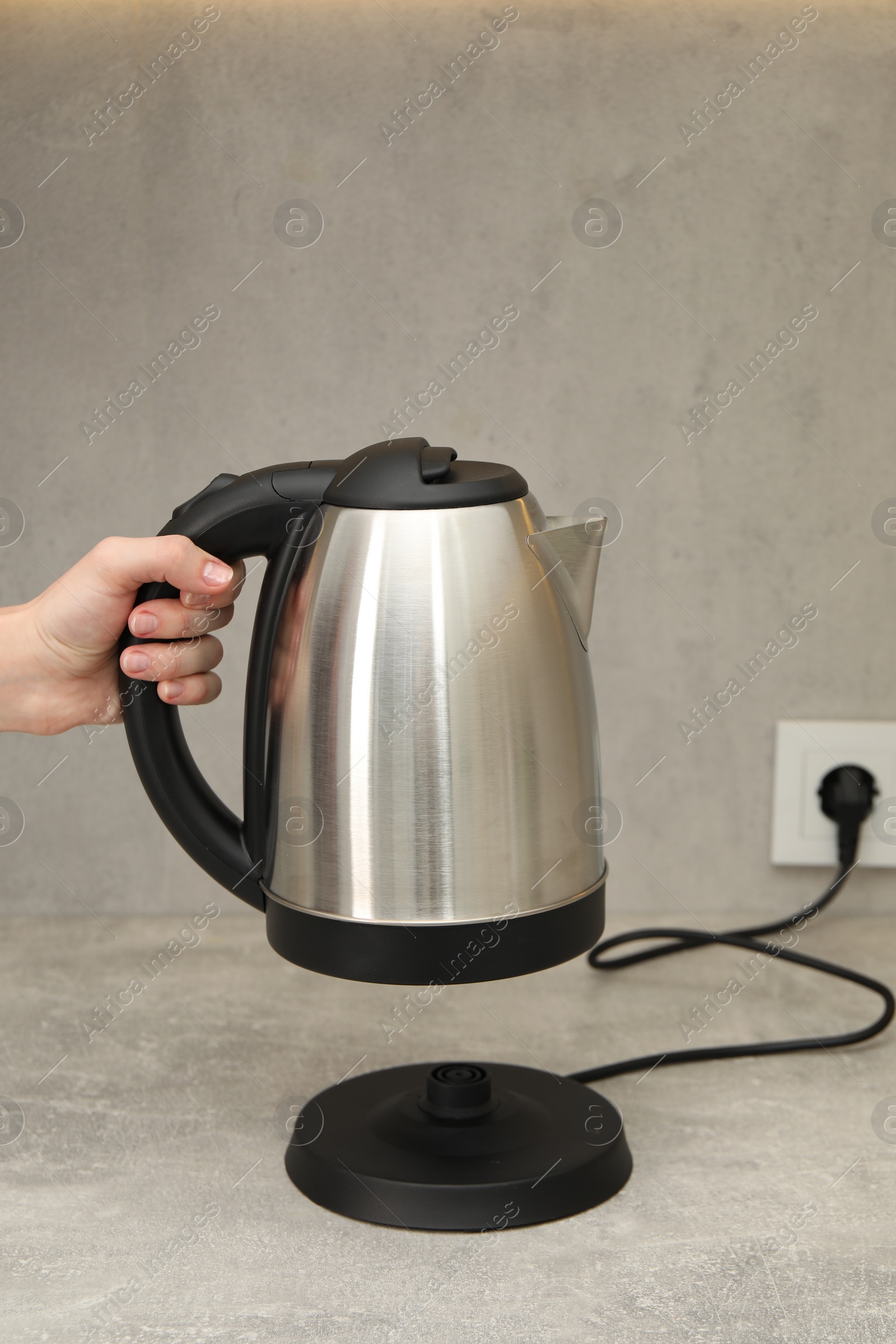 Photo of Woman with electric kettle in kitchen, closeup