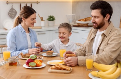 Happy family having breakfast at table in kitchen