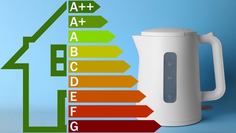 Energy efficiency rating label and electric kettle on light blue background