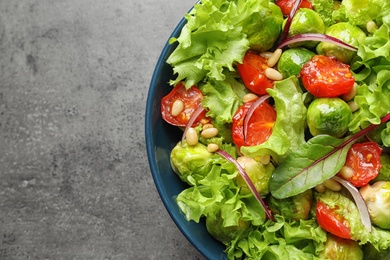 Photo of Bowl of salad with Brussels sprouts on grey background, top view. Space for text