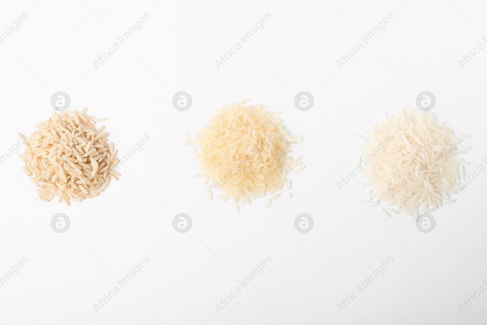 Photo of Different types of uncooked rice on white background, top view