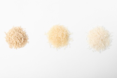 Photo of Different types of uncooked rice on white background, top view