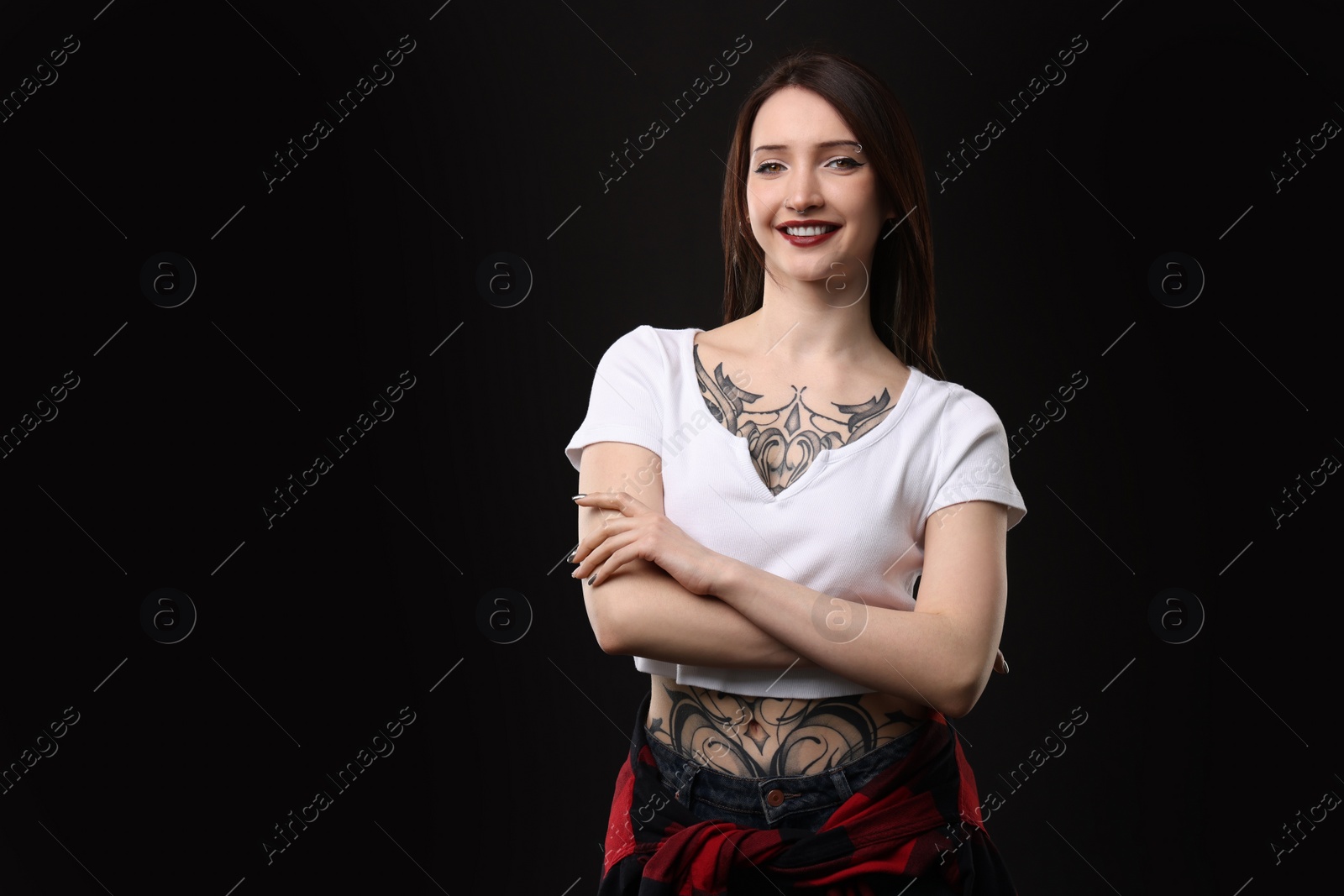 Photo of Portrait of smiling tattooed woman on black background. Space for text