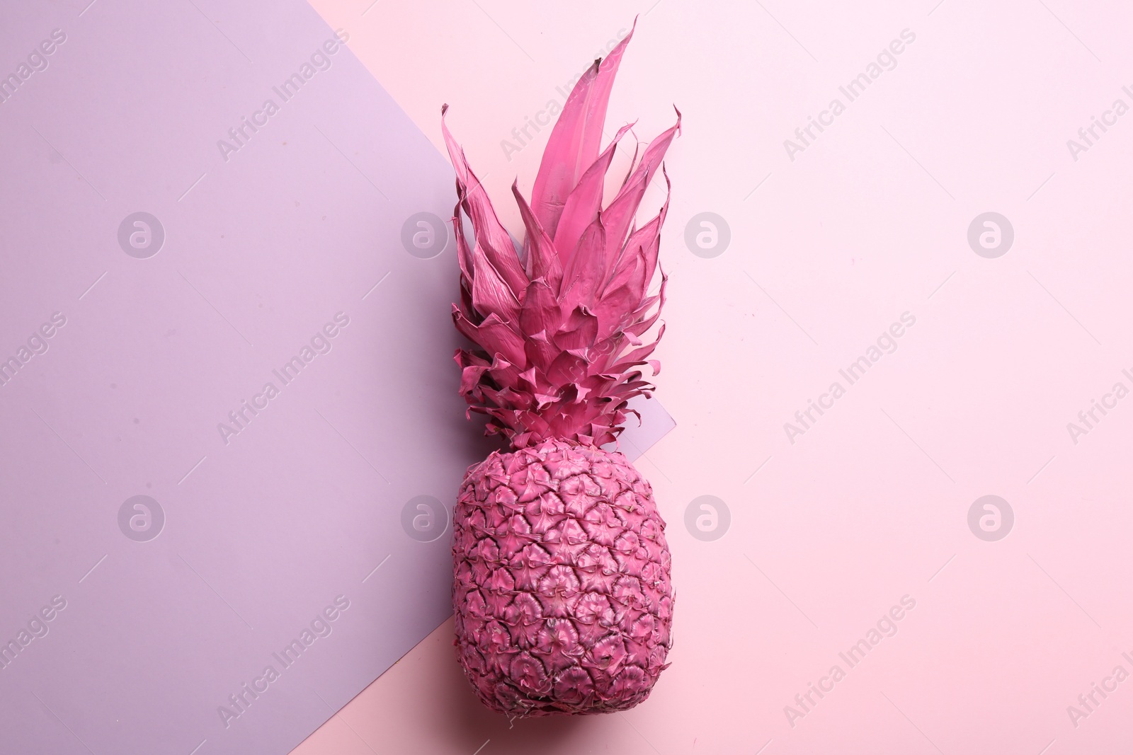 Photo of Pink pineapple on color background, top view. Creative concept