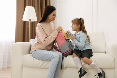 Young mother helping her little child get ready for school at home